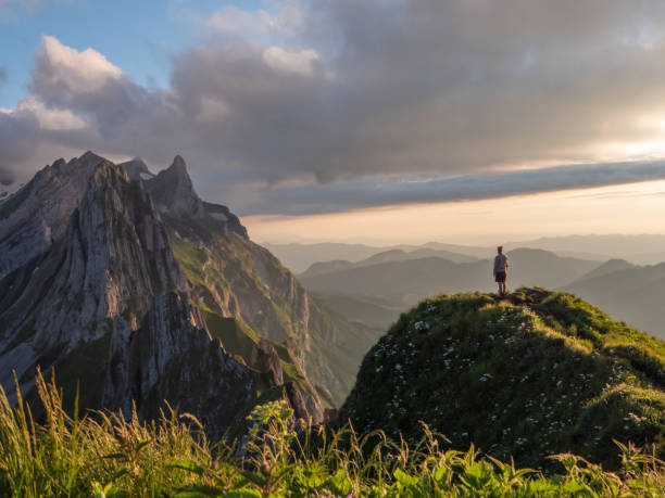 istock Man hiker contemplates sunset from mountain peak 1266292753