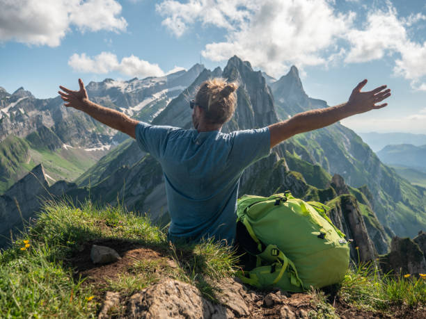 istock Man on mountain top arms wide open embracing freedom and nature 1266292811