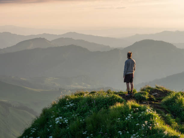 istock Man hiker contemplates sunset from mountain peak 1266292815