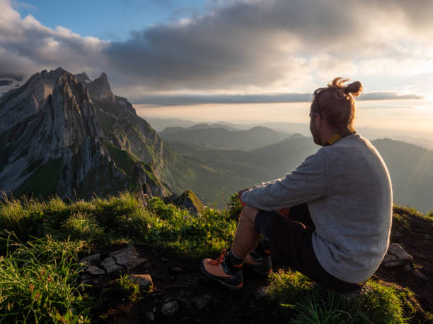 istock Man hiker contemplates sunset from mountain peak 1266292880