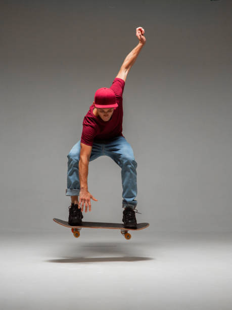 istock Cool young guy skateboarder levitates on skateboard in studio on grey background. Photography about skateboarding tricks 1266296323