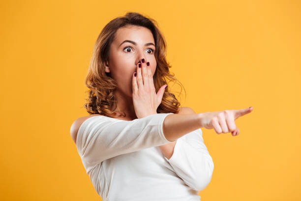 istock Shocked young woman pointing. 1266296489