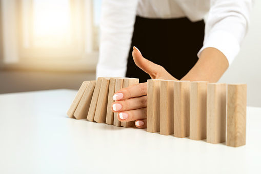 Businesswoman hand stopping falling blocks on table