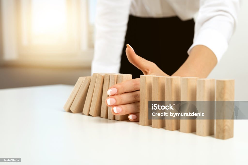 Businesswoman hand stopping falling blocks on table Chain - Object Stock Photo