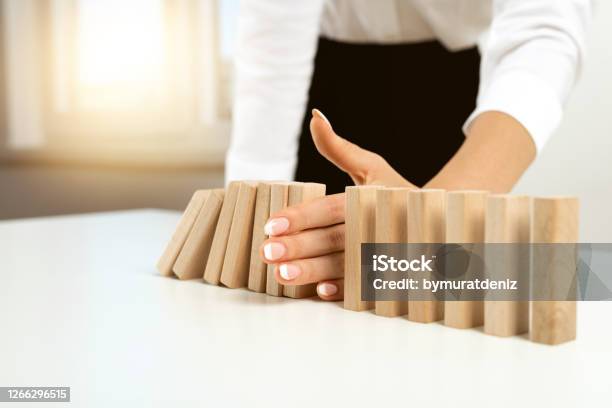 Businesswoman Hand Stopping Falling Blocks On Table Stock Photo - Download Image Now