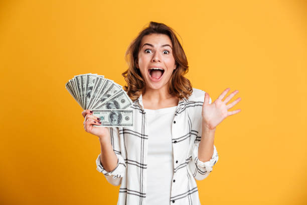 istock Excited young woman holding money looking camera. 1266296878