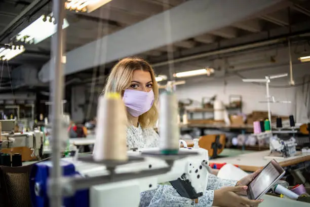 A worker in the textile industry works with a protective mask on his face due to the pandemic of the COVID - 19 virus