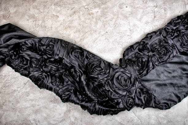istock Monochrome image with black floral vintage wave-shaped fabric on white marble or concrete background 1266297699