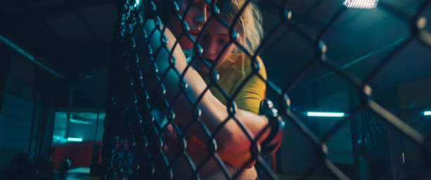 istock MMA fighters training in octagon. Two fights. Women hitting the net in foregroumd 1266297894