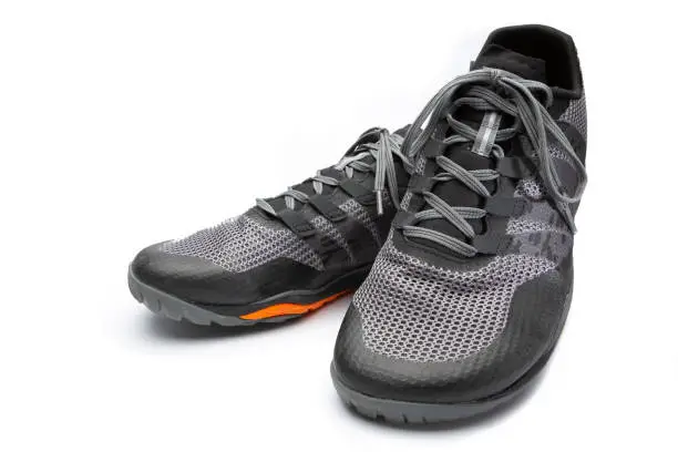 Grey sports shoes (barefoot shoes) with orange accents, exposed with white background