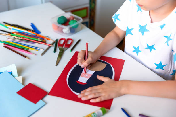 istock Kid hands painting lighthouse at the table with color pencils. 1266299470