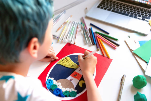 istock Child doing creative hand made work with color paper and plasticine with online lessons. Kids crafts. 1266299472