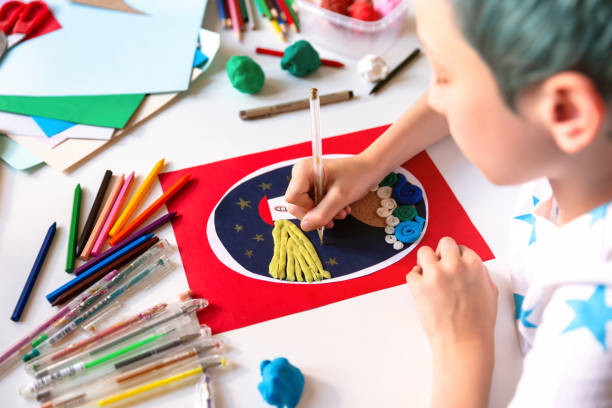 Child doing creative hand made work with color paper and plasticine. Kids crafts.