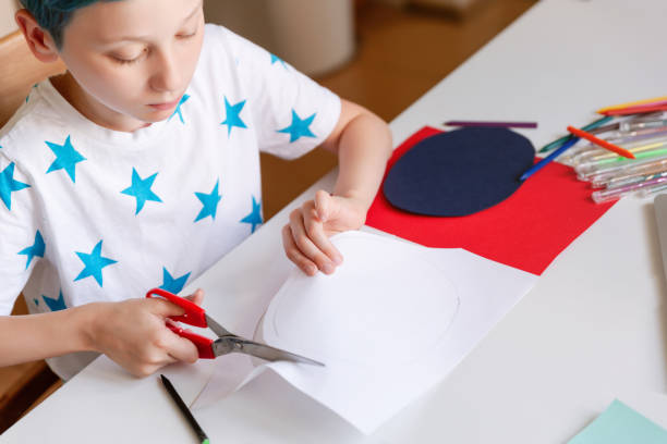 istock Unrecognizable boy cutting paper in arts and crafts class and making handmade gift. 1266299539