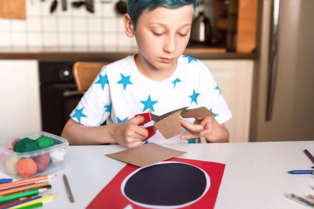 istock Boy cutting paper and making handmade card. Kids art and crafts. 1266299541