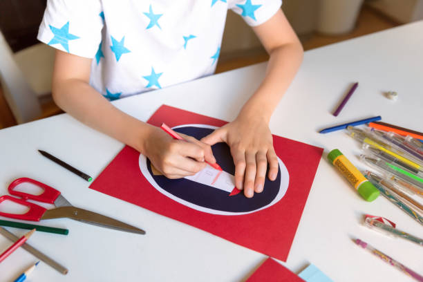 istock Kid hands painting lighthouse at the table with color pencils. 1266299560