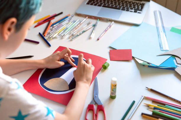 istock Kid boy making hand made card. Kids art and crafts. 1266299569