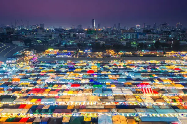 Photo of 02/02/2020 Bangkok, Thailand, Top view of Train Night Market Ratchada (Talad Rot Fai) flea market with plenty of shops with colorful canvas roofs near MRT line at night time in Bangkok