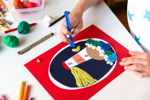 istock Child's hands doing creative hand made work with color paper and plasticine. Kids crafts. 1266300330