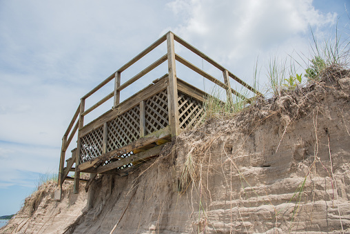 Dangerous beach access stairs at edge of dune erosion from storm damage in Bridgman, Michigan