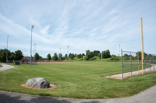 Middle Aged Redhead Father working hard during a baseball coaching session for his daughter at a training pitch on a sunny day