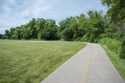 Pedestrian walkway and bicycle path surrounded by lush, native greenery at the community nature reserve in Aurora, Illinois