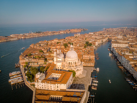 Venice, Italy – April 27, 2019: Venetian cityscape with medieval buildings, boats,  and people on the canal bank