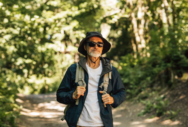 istock Senior man walking in the forest carrying a backpack 1266302541