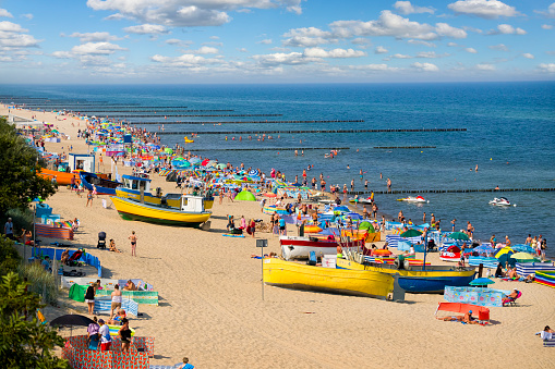 Rewal, Poland - August 10, 2020:Crowded beach in beautiful summer day at Rewal, Poland. Rewal is a small spa resort located in the West Pomeranian Voivodeship, on the coast of the Baltic Sea. In Poland, it is obligatory to cover your face when the distance between people is less than 2 meters