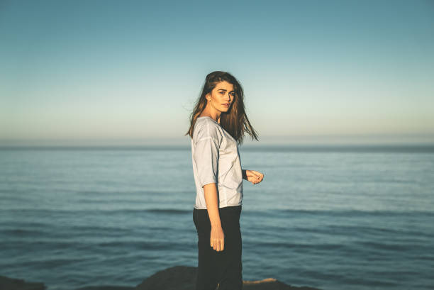 istock Relaxed, smiling woman posing on a rocky coastline. Sunshade 1266311680