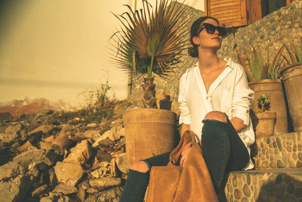 Young woman sitting on a rock. Sea sunset. Lens flares
