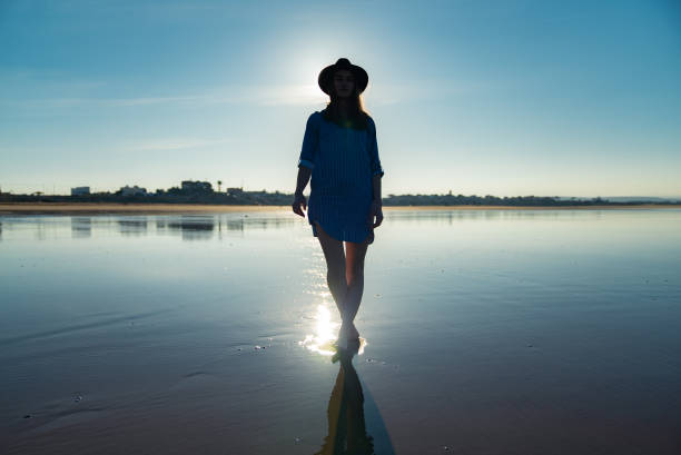 istock Relaxed, smiling woman posing on a beach. Back lit silhouette 1266312331