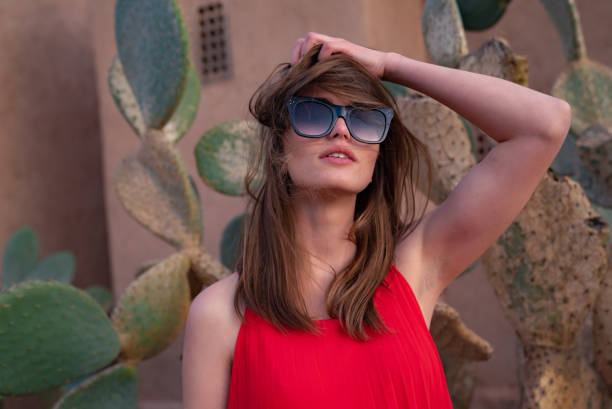 istock Stylish woman posing between succulents. Clay wall behind her 1266312482