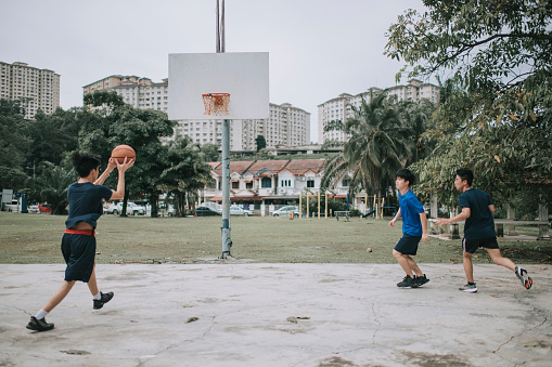 an asian chinese group of teenage boys playing and practicing basketball in the basketball court after school
