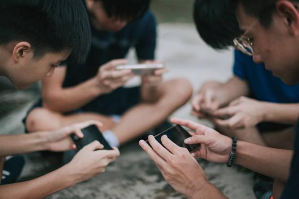 азиатская китайская группа подростков, играющих в мобильную игру на баскетбольной площадке после школы, используя телефон поколения z - match sport leisure games sport apps стоковые фото и изображения