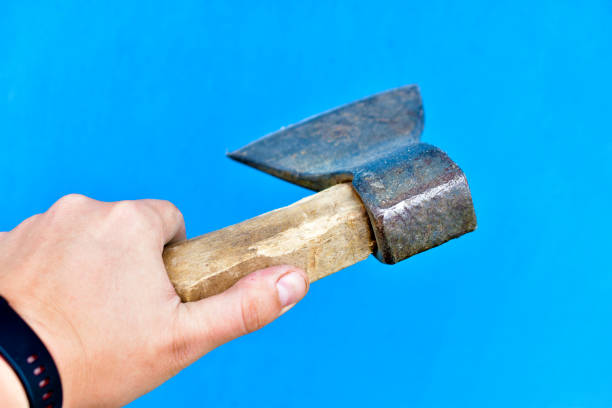 istock Iron axe with wooden handle in hand on a blue background 1266315010
