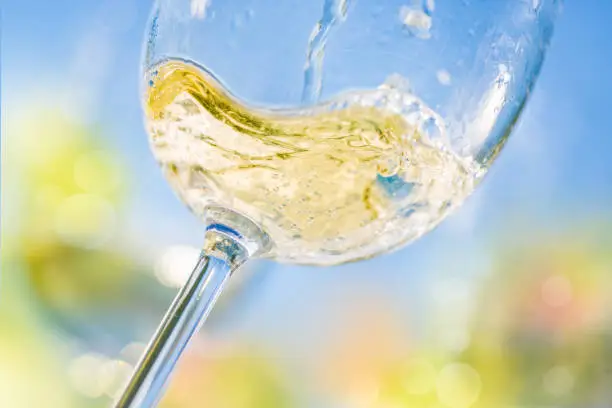 Colorful close-up of pouring white wine in a glass