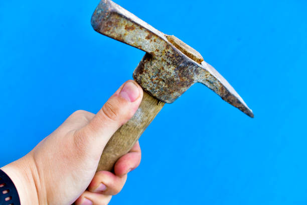 istock Old iron pickaxe in hand on a blue background 1266315271