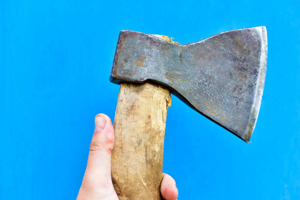 istock Iron axe with wooden handle in hand on a blue background 1266315294