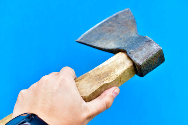 istock Iron axe with wooden handle in hand on a blue background 1266315387