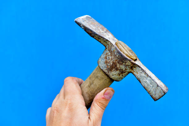 istock Old iron pickaxe in hand on a blue background 1266315412