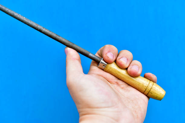 Iron round file with wooden handle in hand on blue background