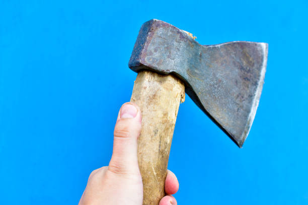 istock Iron axe with wooden handle in hand on a blue background 1266316079