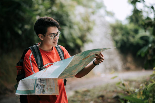 istock Asian chinese smiling young man looking at map in the rainforest jungle 1266316218