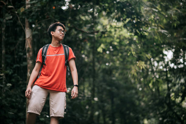 istock Asian chinese smiling handsome young man exploring in the rainforest jungle 1266316437