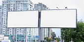 two big white empty billboards on pole at city street commercial advertising concept