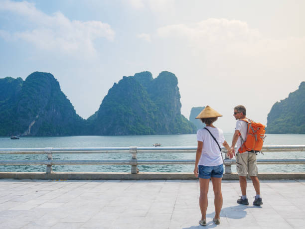 para spaceru ręka w rękę na promenadzie w halong city, wietnam, widok na szczyty skalne ha long bay w morzu. mężczyzna i kobieta zabawy podróżując razem na wakacjach do słynnego punktu orientacyjnego. - halong bay zdjęcia i obrazy z banku zdjęć