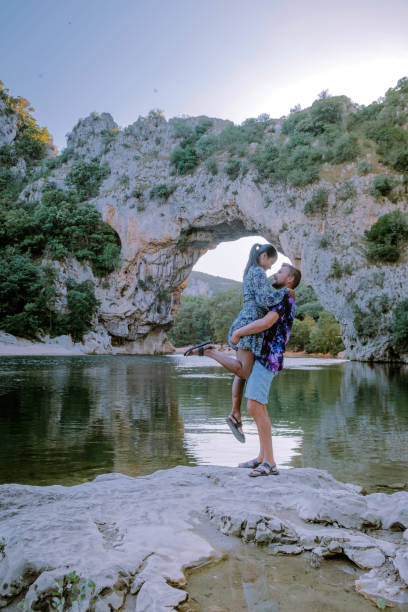 coppia sulla spiaggia sul fiume nell'ardeche france pont d arc, ardeche francia, vista dell'arco narurale a vallon pont d'arc nel canyon di ardeche in francia - canoeing people traveling camping couple foto e immagini stock