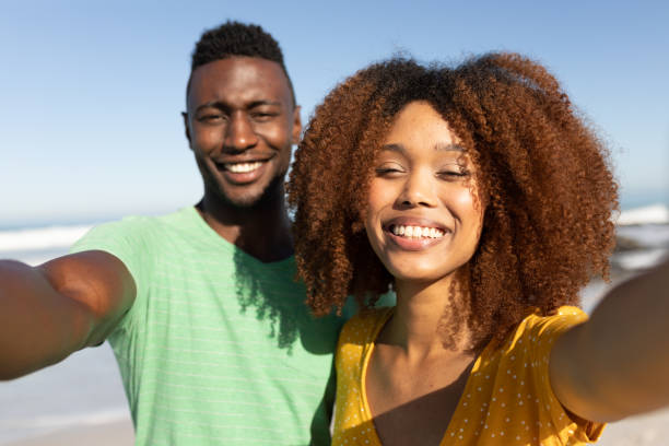 istock Mixed race couple taking selfies on the beach 1266319806