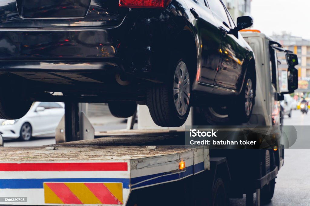 Black Broken Car on a Towing Truck. Closeup Photo. Vehicle Mechanical Problem or wrong parking on the Road. Tow Truck, Towing, Car, Parking, Parking Lot Tow Truck Stock Photo